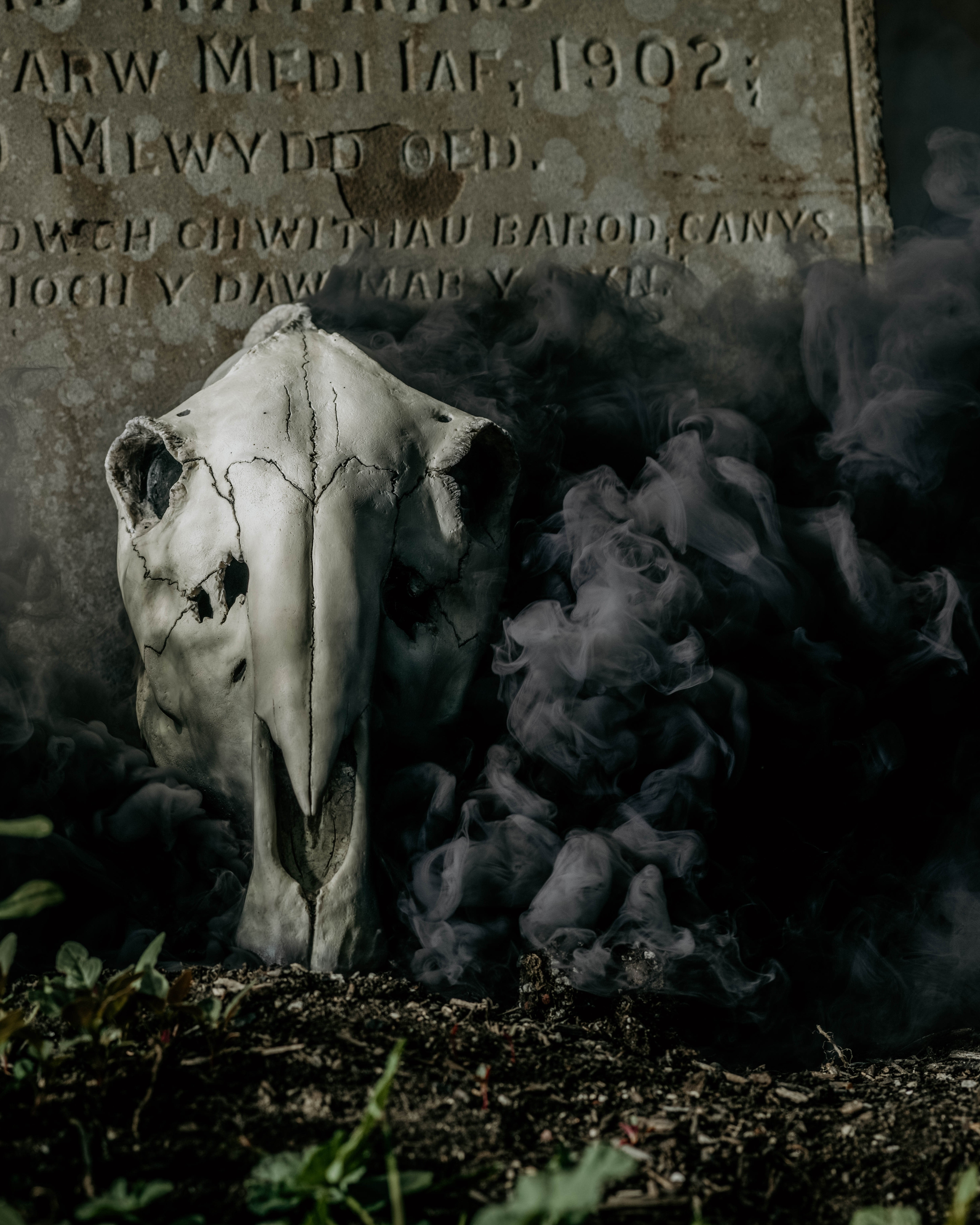 A skull with black smoke pouring from it sits ominously in front of a gravestone in a Dungeons and Dragons campaign